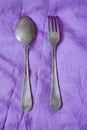 Silver set against the violet background. Silver spoon and fork with an ancient texture. Antique style silver fork and spoon Royalty Free Stock Photo
