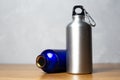 Silver and shiay blue thermo bottle on wooden table.