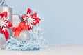 Silver shiny ball with red silk bow closeup and festive christmas decorations and gift boxes on soft light blue color background. Royalty Free Stock Photo