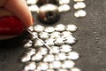 Silver shiny beads and sequins in vintage style are sewn on black coarse fabric. In the frame of the hand. In the frame, a needle Royalty Free Stock Photo