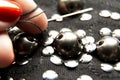 Silver shiny beads and sequins in vintage style are sewn on black coarse fabric. In the frame of the hand. In the frame, a needle Royalty Free Stock Photo