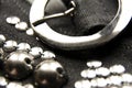 Silver shiny beads and sequins in vintage style are sewn on black coarse fabric. In the frame, a metallic silver buckle