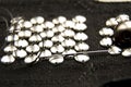 Silver shiny beads and sequins in vintage style are sewn on black coarse fabric. In the frame, a needle with thread Royalty Free Stock Photo