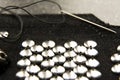 Silver shiny beads and sequins in vintage style are sewn on black coarse fabric. In the frame, a needle with thread Royalty Free Stock Photo