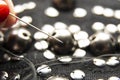Silver shiny beads and sequins in vintage style are sewn on black coarse fabric. In the frame, a needle with thread Royalty Free Stock Photo