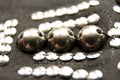 Silver shiny beads and sequins in vintage style are sewn on black coarse fabric