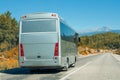 Silver shiny gray modern comfortable tourist bus driving through highway at bright sunny day mountains. Travel and coach tourism Royalty Free Stock Photo