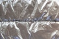 Silver shiny metal creased background. Glitter grey color, thin sheet foil texture with dented uneven surface