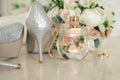 Silver shoes of the bride , perfume, bouquet and wedding rings on the dressing table near the mirror.