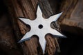 Silver shuriken rests on dark wooden texture