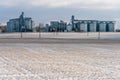 Silver silos against the blue sky in winter. Grain storage in winter at low temperatures. A wheat field covered with snow, the