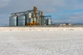 Silver silos against the blue sky in winter. Grain storage in winter at low temperatures. A wheat field covered with snow, the