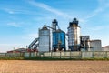 Silver silos on agro manufacturing plant for processing drying cleaning and storage of agricultural products, flour, cereals and Royalty Free Stock Photo