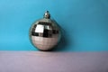 Silver snowy small round xmas festive Christmas ball, Christmas toy plastered over sparkles on a gray blue background Royalty Free Stock Photo