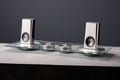 silver speaker system on a minimalist glass table against a neutral gray background