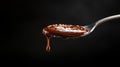 A silver spoon drips with rich, glossy chocolate sauce set against a dark background Royalty Free Stock Photo