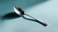 Silver spoon on turquoise background with soft shadow effects Royalty Free Stock Photo
