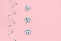 Silver streamers serpentine and bows on pink background in minimal style. Concept decorations for celebration, party, holiday, Royalty Free Stock Photo