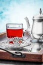 Silver teapot with a cup fruit tea in a cup holder on a mirror tray Royalty Free Stock Photo
