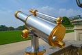 Silver telescope with golden elements mounted to look into a historic park