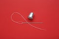 Silver thimble, needle and thread on red background, flat lay Royalty Free Stock Photo