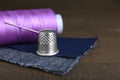 Silver thimble, thread and needle on wooden table, space for text. Sewing accessories Royalty Free Stock Photo