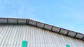 A silver tin roof of sport center building with a bright blue sky background. Royalty Free Stock Photo