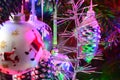 Silver tinsel on Christmas tree. Blured holiday background with garland, glass toys, balls, lights. Colorful decoration