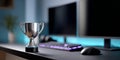 Silver trophy cup on desk with dual computer monitors, keyboard, and mouse in modern workspace with blue ambient lighting Royalty Free Stock Photo