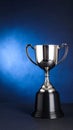 Silver trophy cup with handles on a black base against a blue gradient background Royalty Free Stock Photo