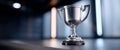 Silver trophy cup placed on a smooth surface with blurred modern interior background and soft lighting Royalty Free Stock Photo