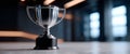 Silver trophy cup standing on a marble surface with blurred modern interior background and soft lighting Royalty Free Stock Photo