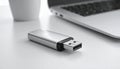 Silver USB flash drive and a blurred cup next to a laptop Keywords: USB drive, flash drive, storage, data Royalty Free Stock Photo