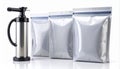 Silver Vacuum Pump and Three Shiny Vacuum Sealed Bags on White Surface Royalty Free Stock Photo