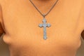 Silver vintage crucifix pendant or cross sign and chain necklace and close-up orange sweater. Easter festival. Faith. Christian. Royalty Free Stock Photo