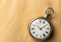 Silver vintage pocket watch with hands and numbers on a round dial. Old retro clock on a beige background with place for Royalty Free Stock Photo