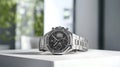 Silver watch with a black face sits on a white surface Royalty Free Stock Photo