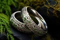 silver wedding bands nested on a mossy river stone