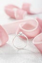 Silver wedding diamond ring on white sparkle background with pink ribbon Royalty Free Stock Photo