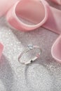 Silver wedding diamond ring on white sparkle background with pink ribbon Royalty Free Stock Photo