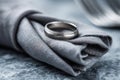 Silver wedding ring on a folded gray cloth with a blurred white cup in the background Royalty Free Stock Photo