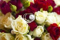 Silver wedding rings on wedding bouquet of red and white roses Royalty Free Stock Photo