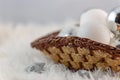 Silver and white Christmas balls in a basket that stands on a fluffy fur blanket