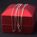 silver or white gold jewelry chain on a red gift box. Royalty Free Stock Photo