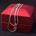 silver or white gold jewelry chain on a red gift box. Royalty Free Stock Photo