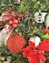 Silver white and red ornaments hanging from greenery and surrounded by additional red and silver ornaments and ribbon. Royalty Free Stock Photo
