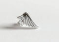 Silver wing-shaped ring with elegant curved design on white background Royalty Free Stock Photo