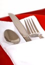 Silverware in a folded napkin on a red plate