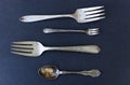 Weathered silverware of forks and spoons against black background