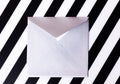 Silvery paper envelope on striped black and white background